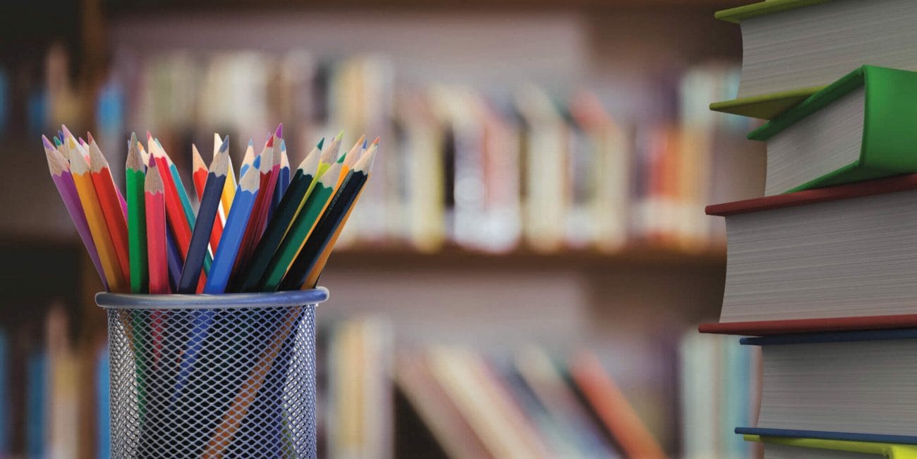 Digital composite of Pencils and stack of books with library background