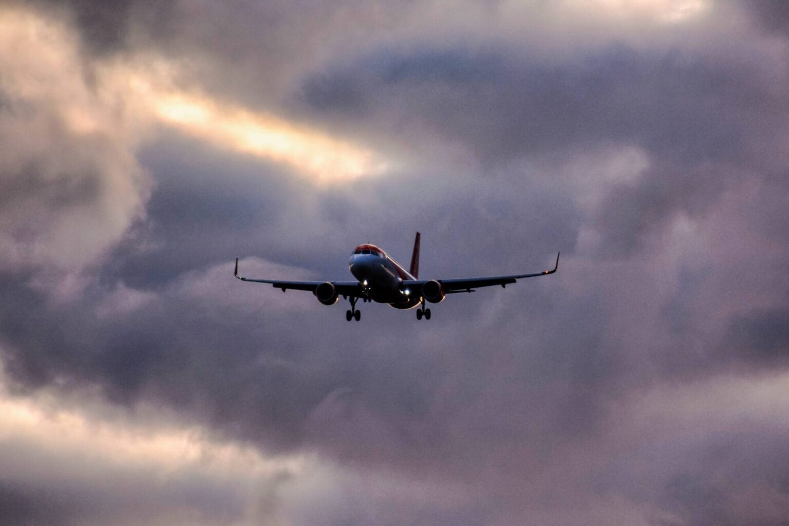 A low angle shot of an airplane descending from a clouded sky